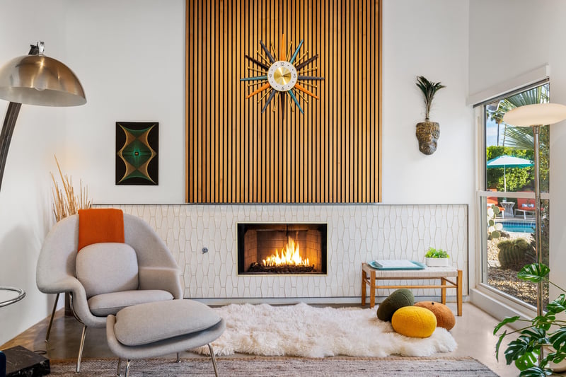 Unwind by your crackling fireplace in this stylish living space featuring midcentury design and pool views through floortoceiling windows.