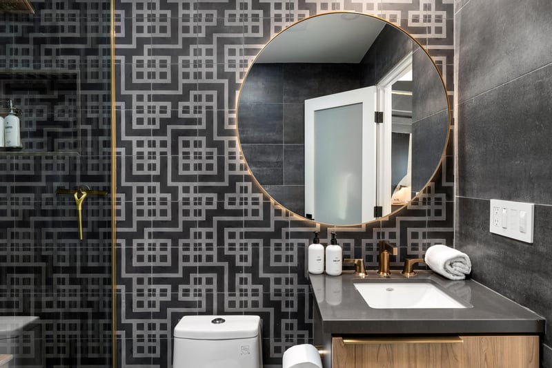 Step into your stylish bathroom featuring modern geometric tiles, brass fixtures, and premium amenities for your refreshing morning routine.