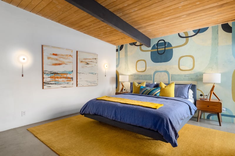 Drift off to sleep in your stylish midcentury bedroom, where warm wood beams and playful geometric wallpaper create the perfect retreat.