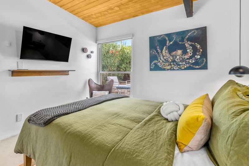 Sink into your dreamy retreat with olive green linens, warm wood ceilings, and modern touches creating the perfect escape.