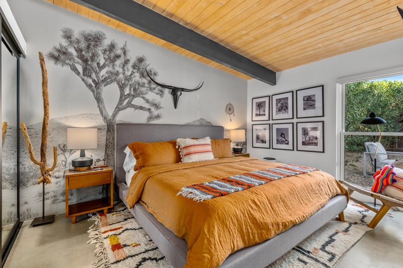 Drift off in this desertinspired bedroom where warm orange bedding meets artistic touches and exposed beams create your perfect retreat.