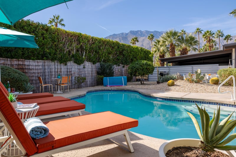 Your private poolside retreat features mountain views, comfortable loungers with towels, and a desert garden backdrop perfect for relaxation.