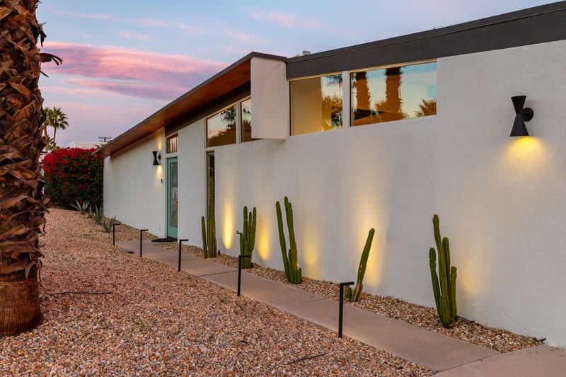 Modern desert architecture showcases clean lines and striking cacti landscaping under a painted sunset sky.