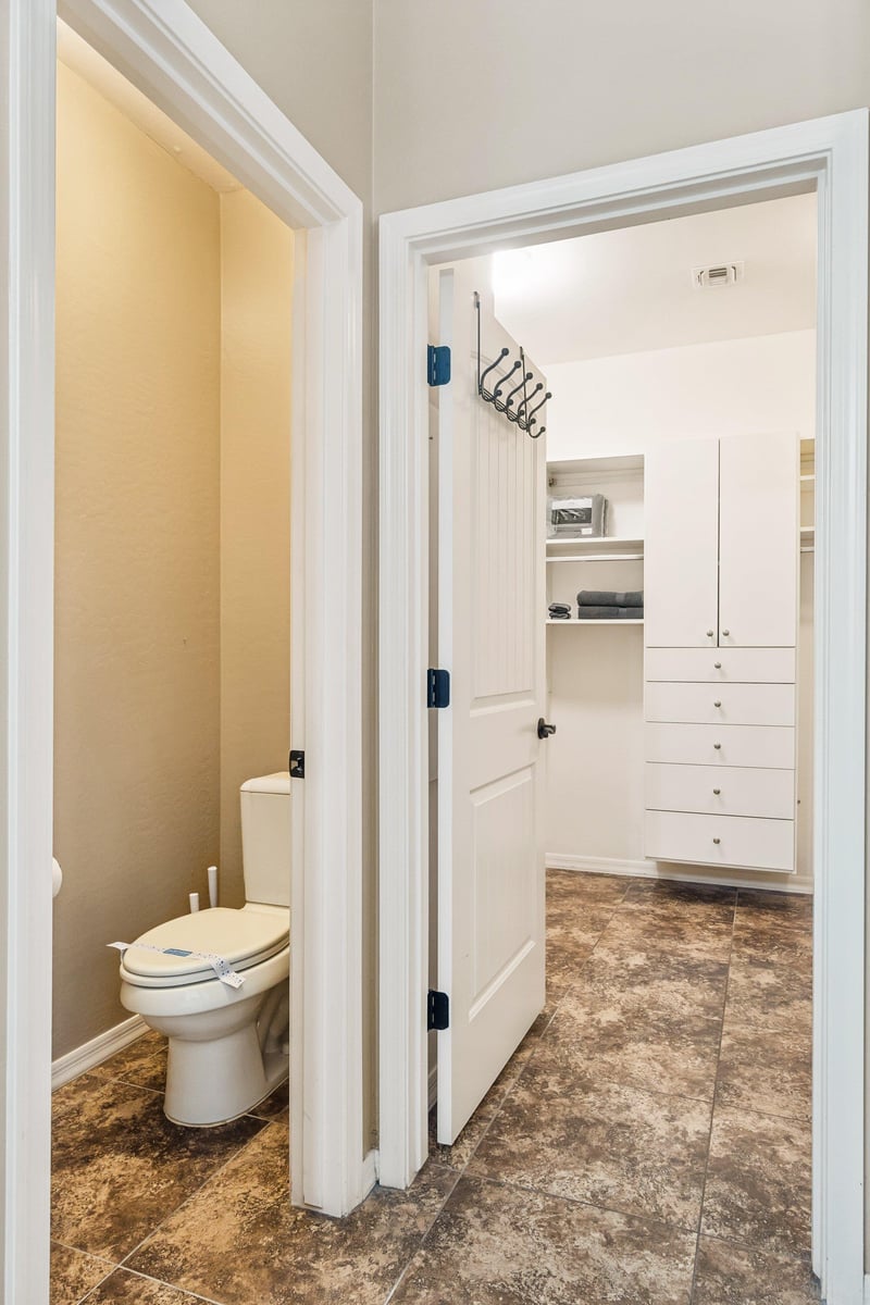 Toilet next to closet with private door.