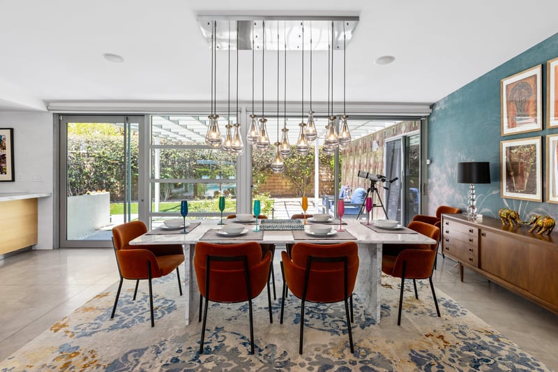 Dine at a marble table set for 6 under a beautiful chandelier. View of the front door just off to the left of the table.