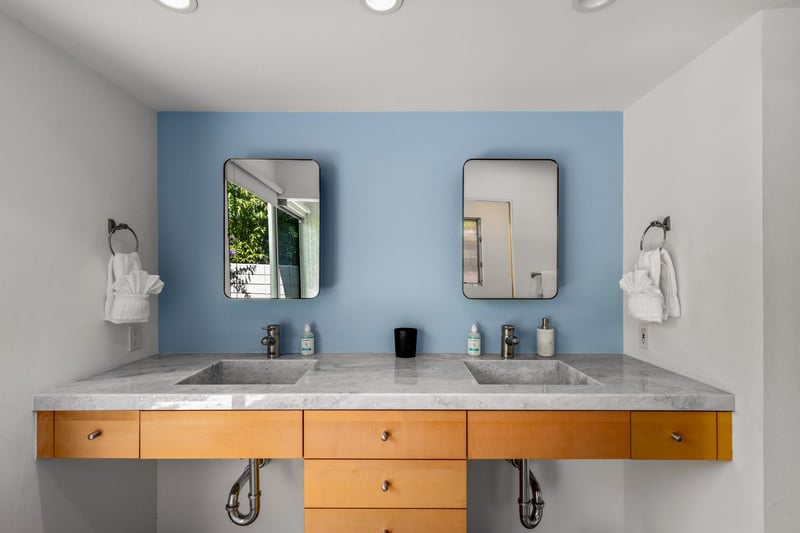 Stunning primary bathroom with dual vanity sink, large sliding doors with natural lighting, and standalone shower with its own sliding door to turn it into an indooroutdoor shower.