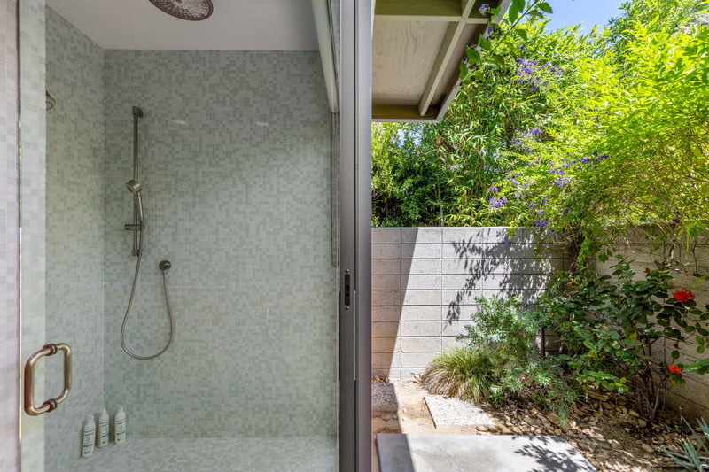 Standalone shower with its own sliding door to turn it into an indooroutdoor shower.