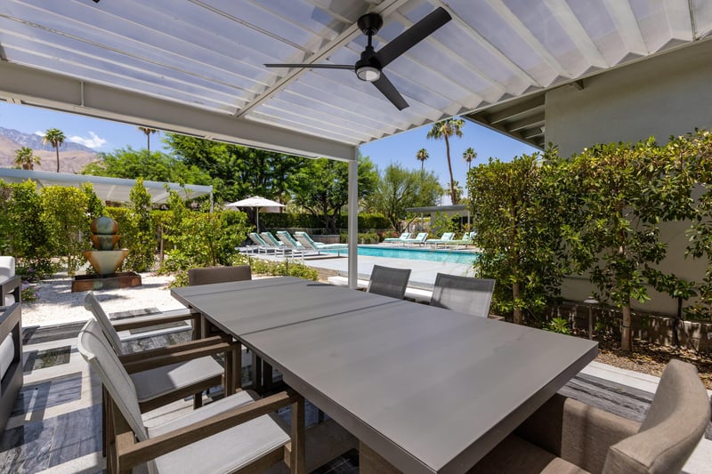 Outdoor dining area under pergola with fan, table, and seating for 6 guests.