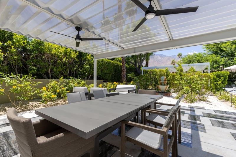 Outdoor dining area under pergola with fan, table, and seating for 6 guests.