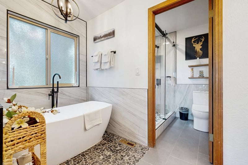 Ensuite bathroom with dual vanity sinks, modern fixtures, standalone tub, and walkin shower.