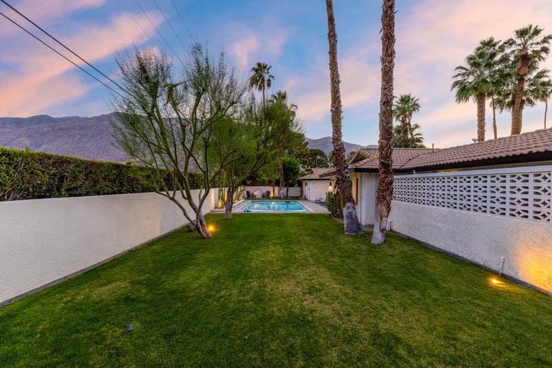 Grassy lawn located on the opposite side of the pool and firepit area.