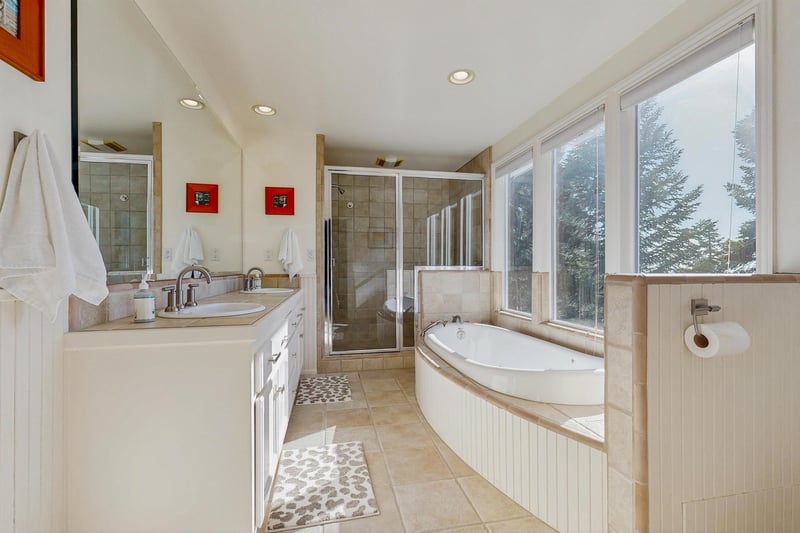 Ensuite bathroom equipped with a standalone jet tub, stand alone shower, dual vanity sink, and plenty of natural lighting.