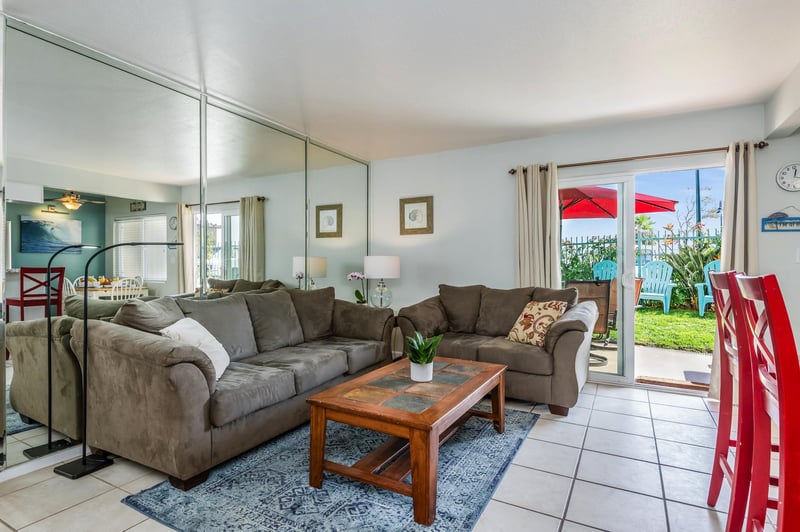 Living room with sliding glass doors out to the patio, grass, and 10 steps to the beach