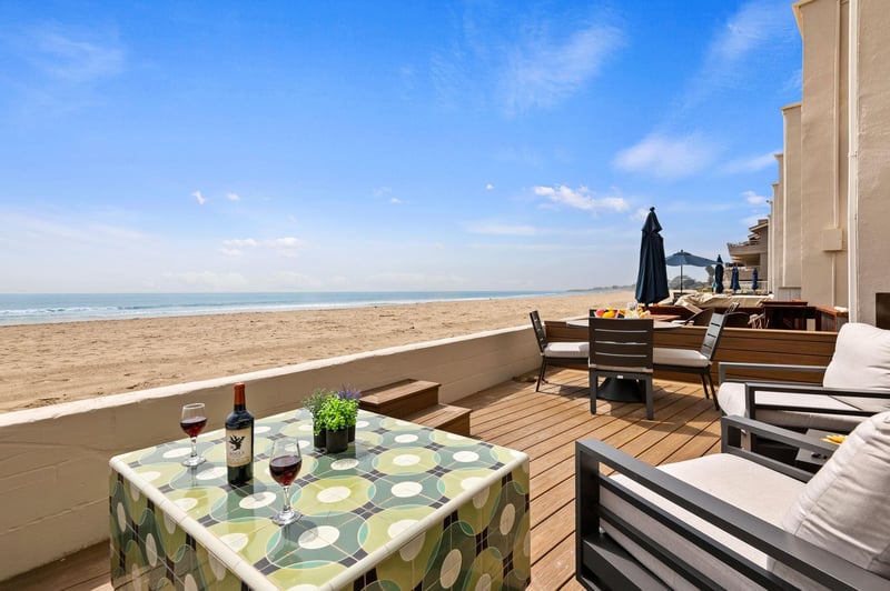 Incredible beach Front deck with comfortable couch, chairs, and dining area.