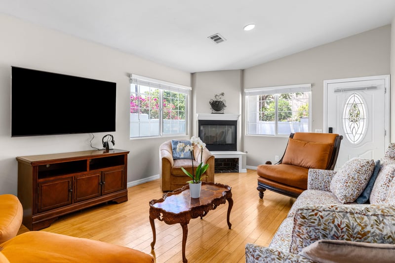 Entryway flows into the living room with a flatscreen TV, fireplace, and ample seating.