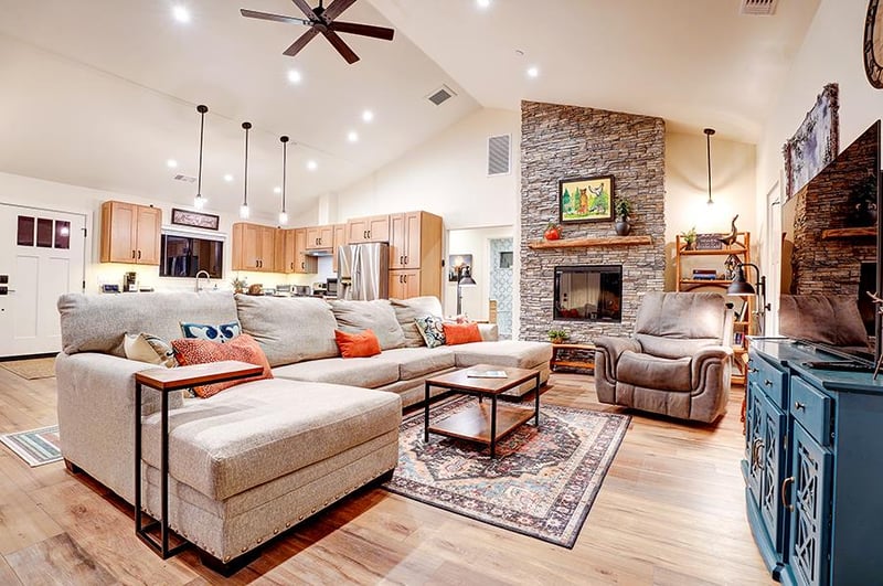 Living room with large stone fireplace, flatscreen TV, and ample seating.