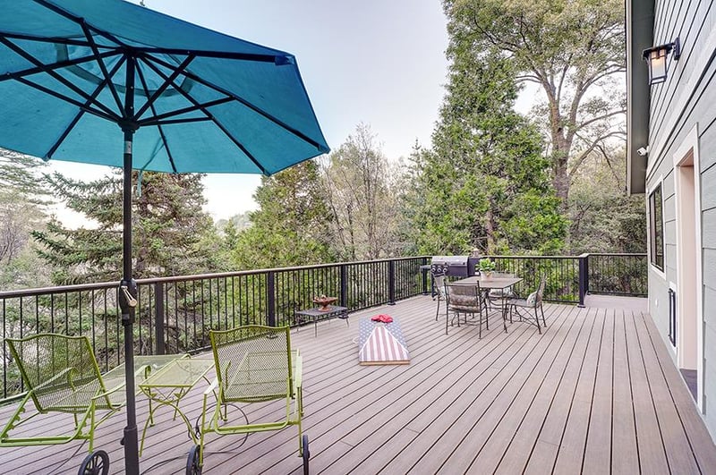 Spacious deck with mountain and forest views, outdoor games, BBQ, and deck seating.