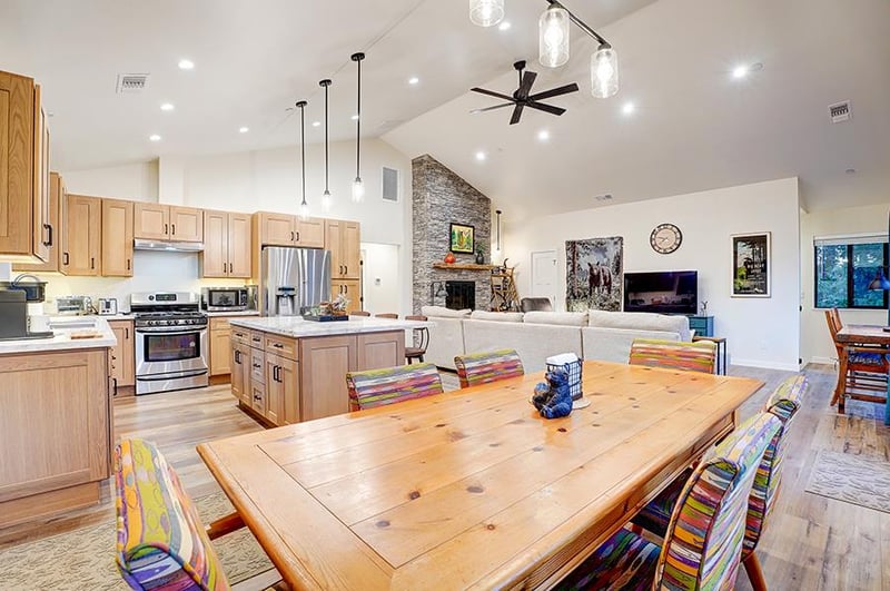 Dining area with table and chairs for 6 guests. Kitchen with stainless steel appliances, kitchen island with seating, and cooking essentials.