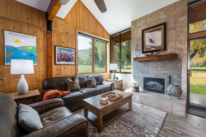 Floortoceiling wood paneling, a gorgeous stone fireplace, and views of the golf course beyond — Park Avenue 236 is mountain lodge living perfected.