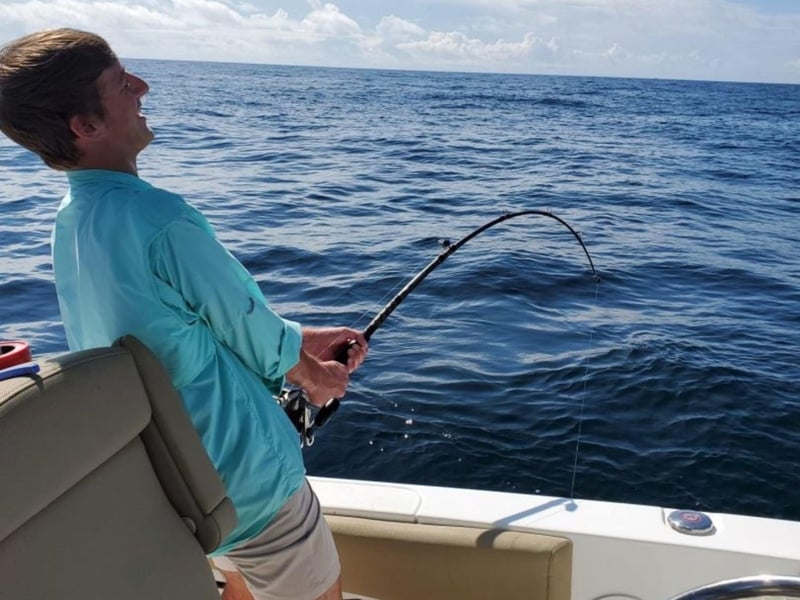 An angler fishing off the side of the boat with All Out Fishing Charters