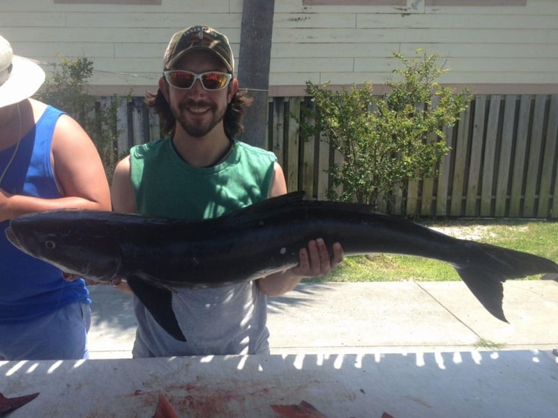 An angler holding his catch on the dock in Pensacola Beach, Florida