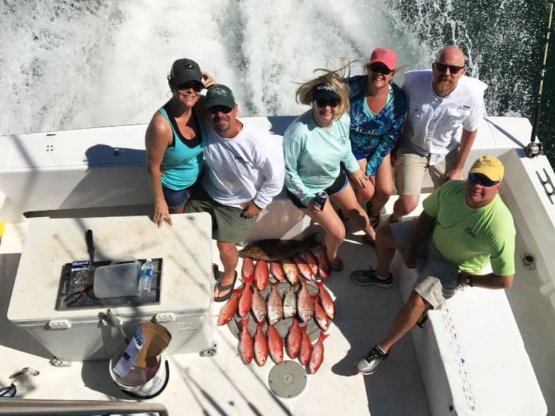 A group showing off their catches on the back of the boat
