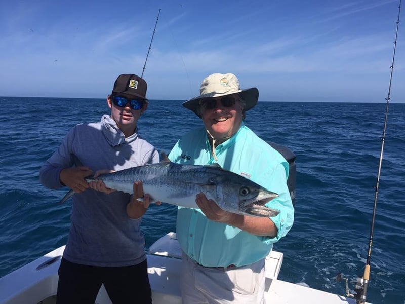 Two men showing off their caches on the back of the boat