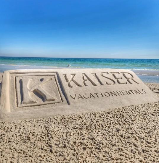sand sculpture with Kaiser Vacation Rentals logo on the beach in Gulf Shores, Alabama