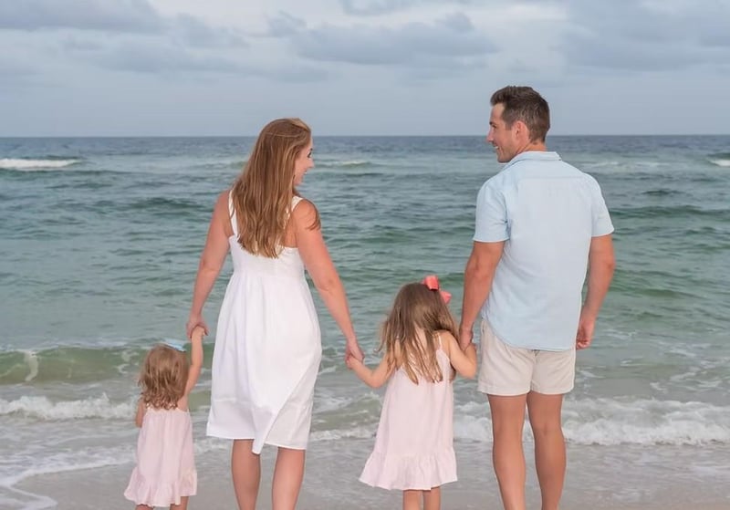 Couple walking hand in hand along the shoreline with ocean waves behind them during a beach photography session.