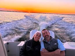 Couple relaxing at the back of a boat during a sunset cruise with glowing skies over the Gulf.