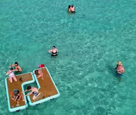 Aerial view of people relaxing on floating mats in clear turquoise water at Crab Island in Florida