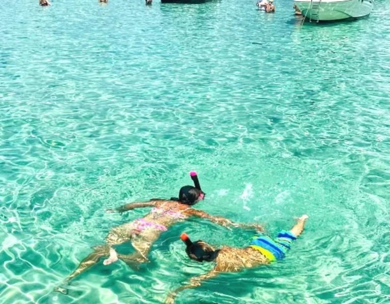 Two people snorkeling in bright, clear green water at Crab Island in Santa Rosa Beach