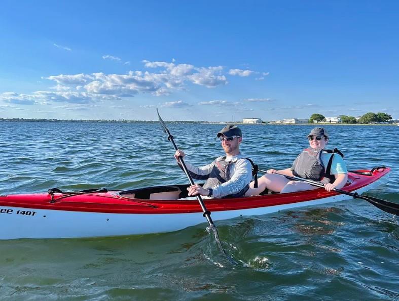 Couple smiling while kayaking at sunset in Little Sabine Bay near Pensacola Beach.