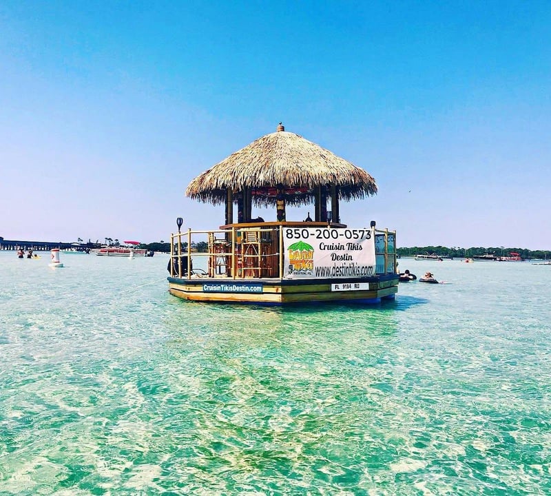 Tiki boat floating in shallow emerald water at Crab Island in Destin, Florida.