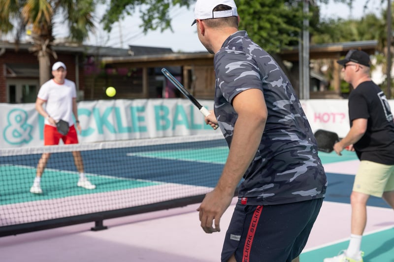 Closeup of players hitting a pickleball during a match on outdoor courts