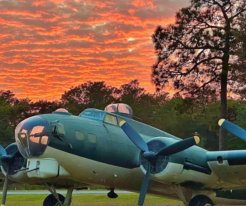 Vintage military aircraft parked outdoors at sunset with colorful sky in the background