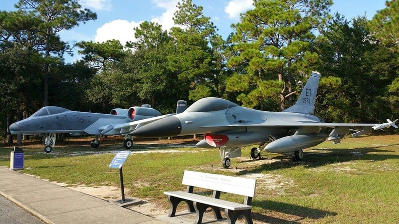 Fighter jets on outdoor display at Air Force Armament Museum surrounded by trees