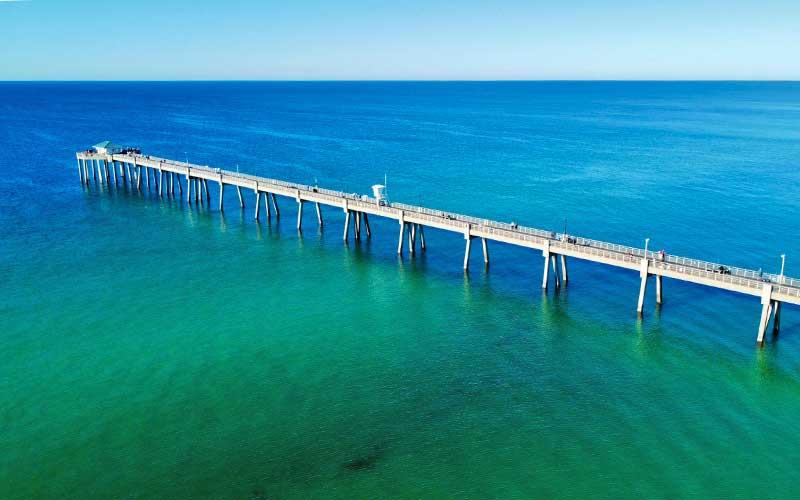 Aerial view of Okaloosa Island Pier extending into clear emerald waters in Fort Walton Beach