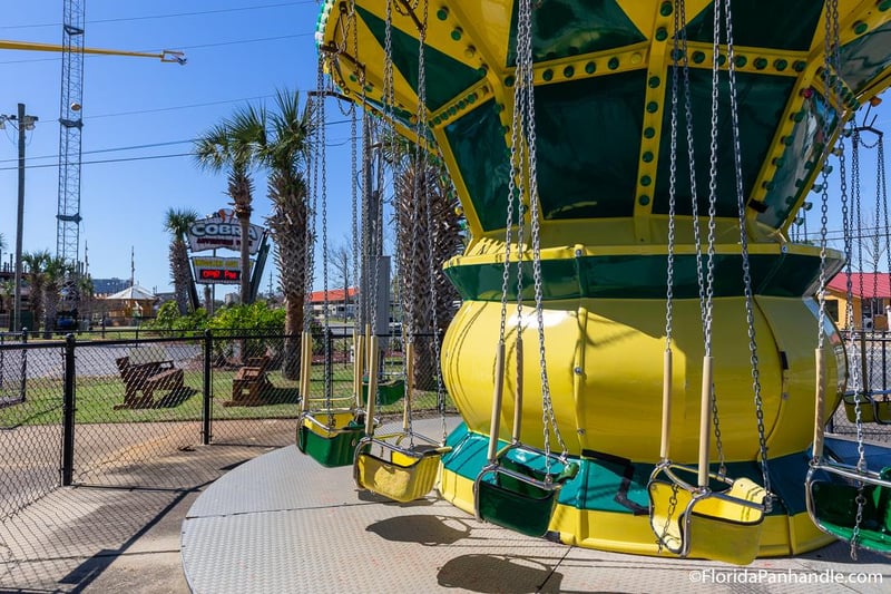 Swing ride attraction with green and yellow seats at Cobra Adventure Park