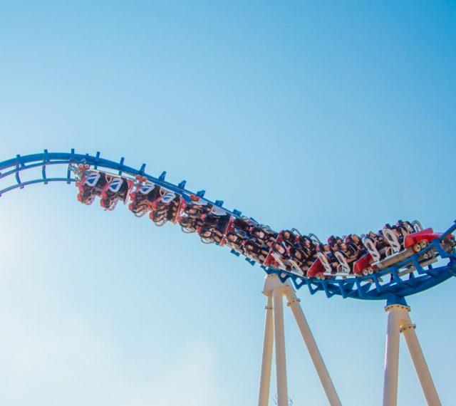 Roller coaster with riders at Cobra Adventure Park against clear blue sky