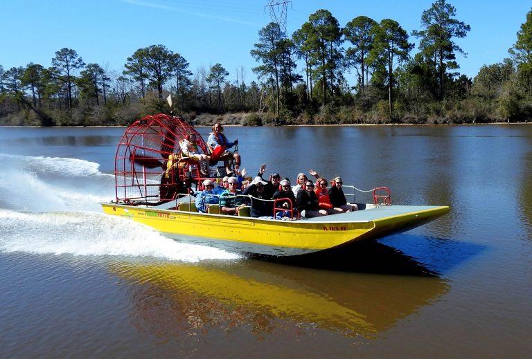 Group riding highspeed airboat through calm waterway at Airboat Adventures