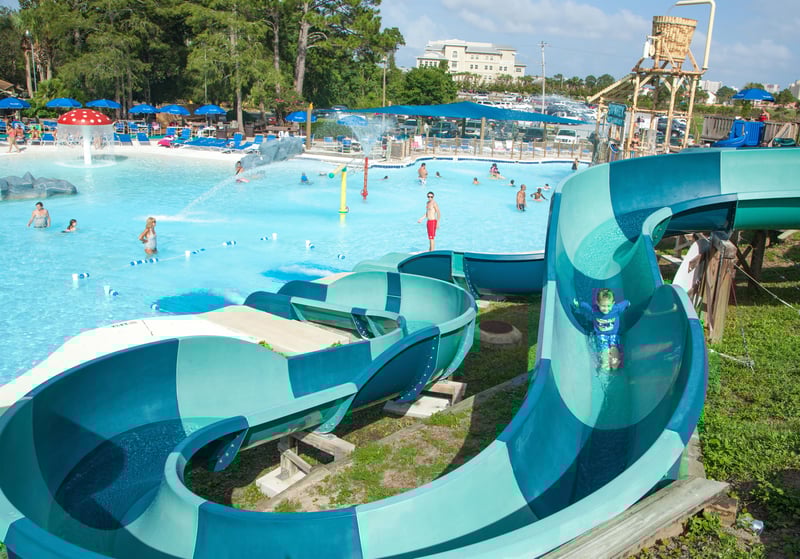 Child riding curved water slide into pool at Shipwreck Island Waterpark