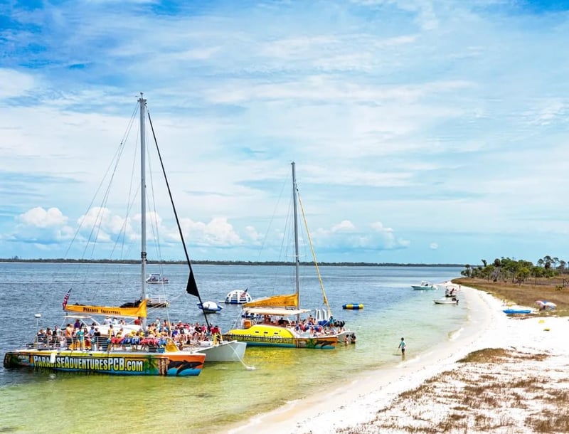 Two catamarans anchored by a sandy beach with guests enjoying the water in Panama City Beach