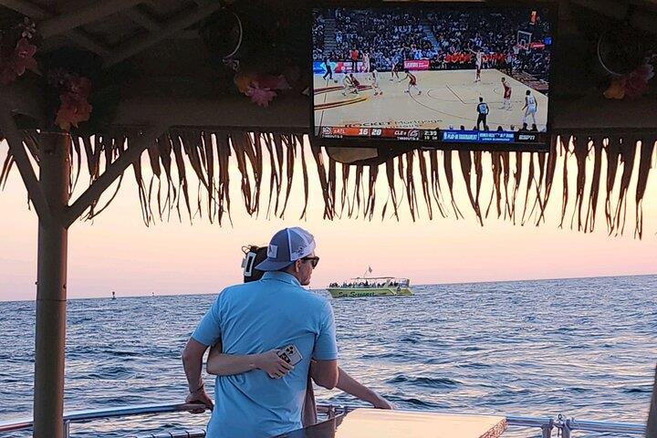 Couple relaxing on tiki boat watching sunset over Panama City Beach