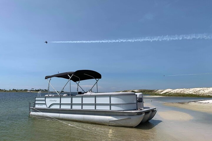 Pontoon boat anchored near sandy shoreline in Pensacola Beach