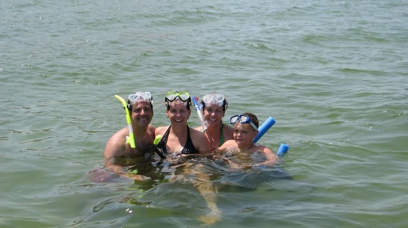 Family snorkeling together in clear water in Pensacola Beach