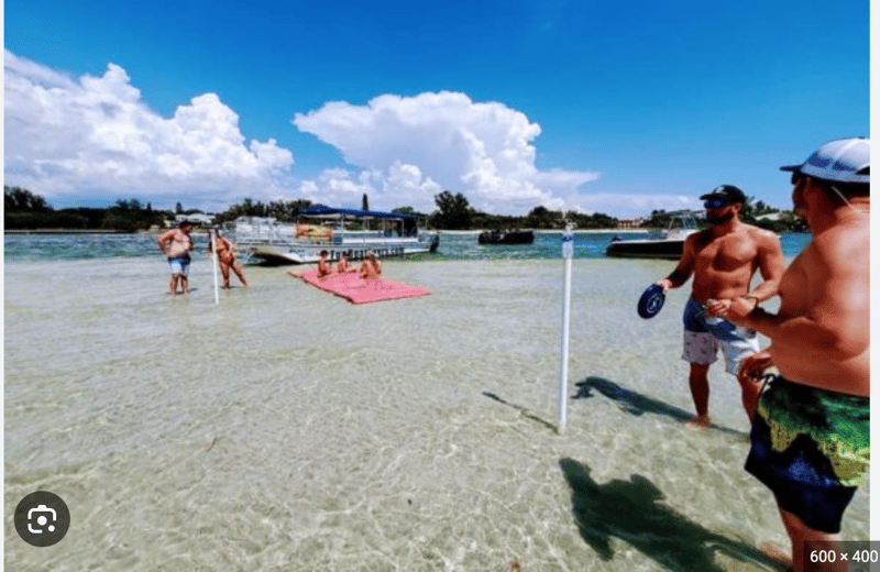 1363130 Friends Enjoying Beach Games And Shell Hunting On The Sandbar