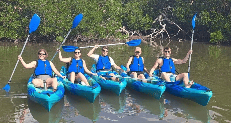Family paddling tandem kayaks through scenic mangrove forests