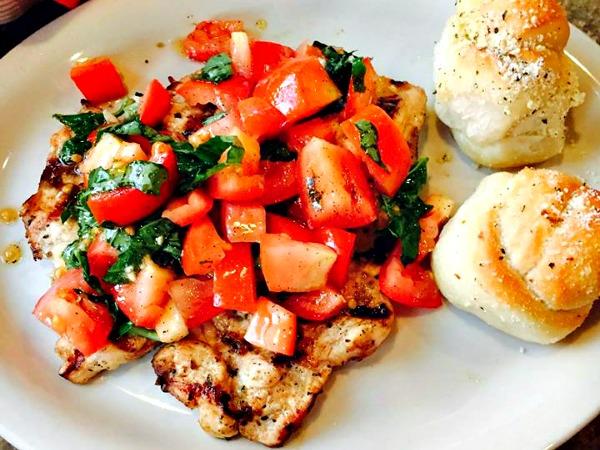 baked fish dish topped with chopped tomatoes at Francos Italian restaurant in Orange Beach, AL