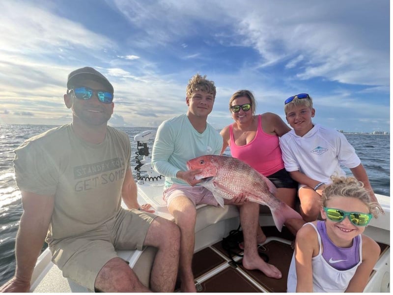 A family holding a fish aboard AlLin off the coast of Destin, Florida